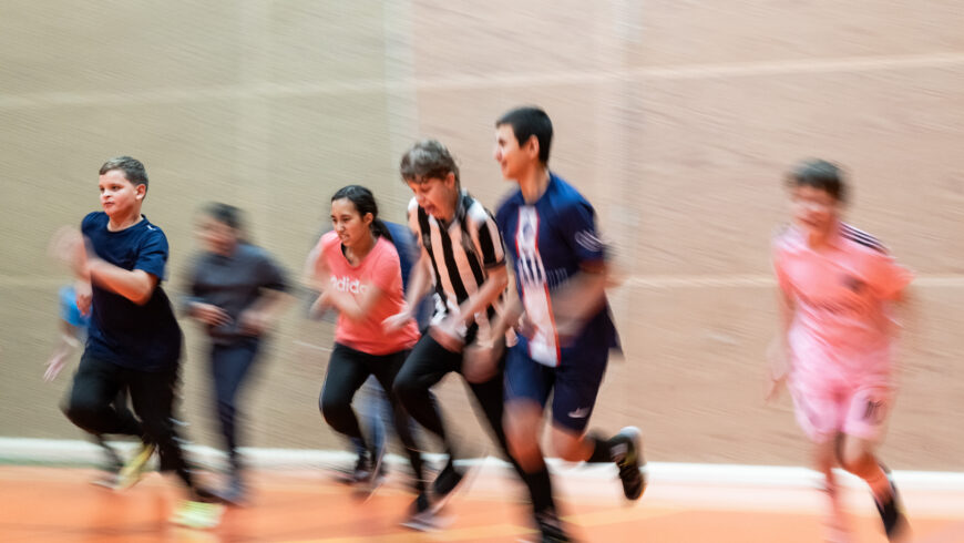 Sex barn som springer snabbt tillsammans inomhus i en gympahall