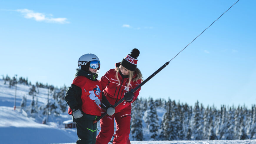 Barn i en ankarlift med en vuxen liftvakt bredvid