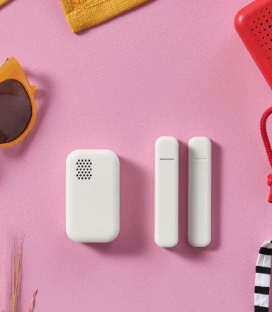 Gula solglasögon, en röd högtalare och tre vita tekniska saker mot en rosa bakgrund